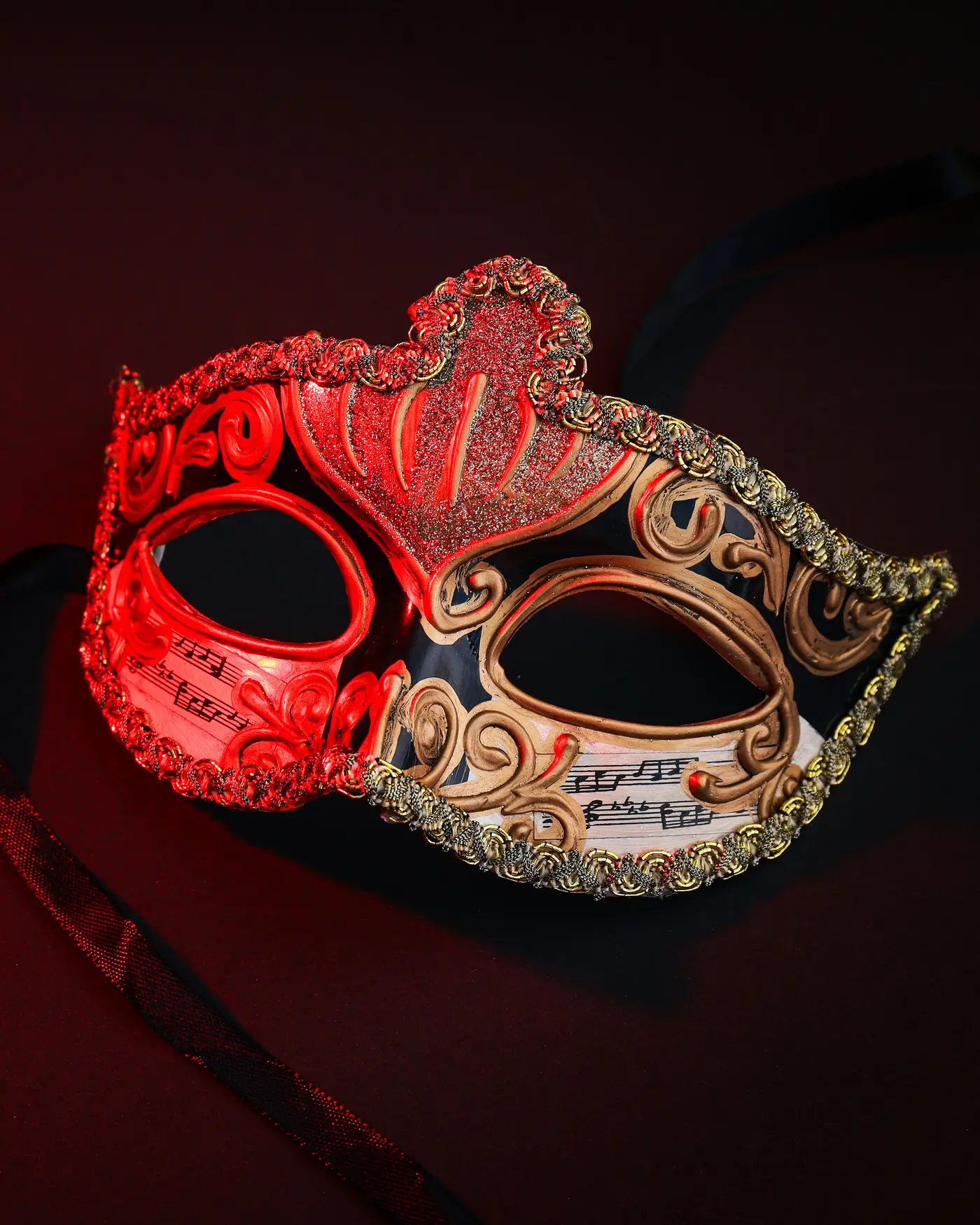 Masque vénitien rouge et or posé sur un velours sombre